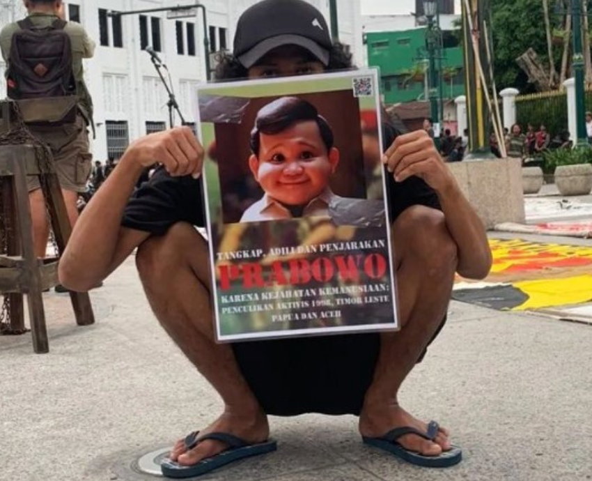 person squatting holding a sign