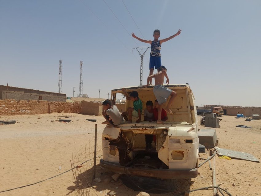 children playing on a van in a desert refugee camp