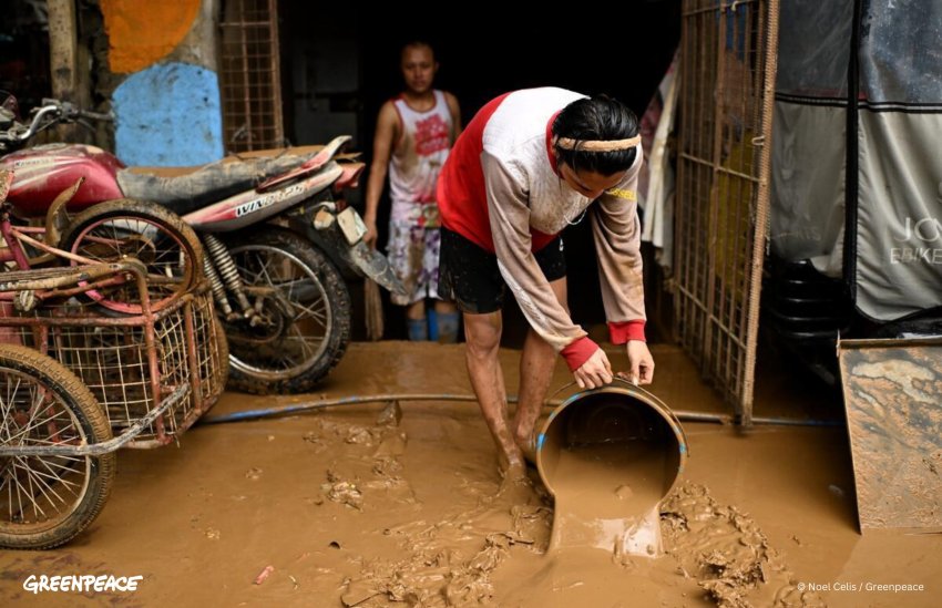 woman bucketing mud from her flooded home