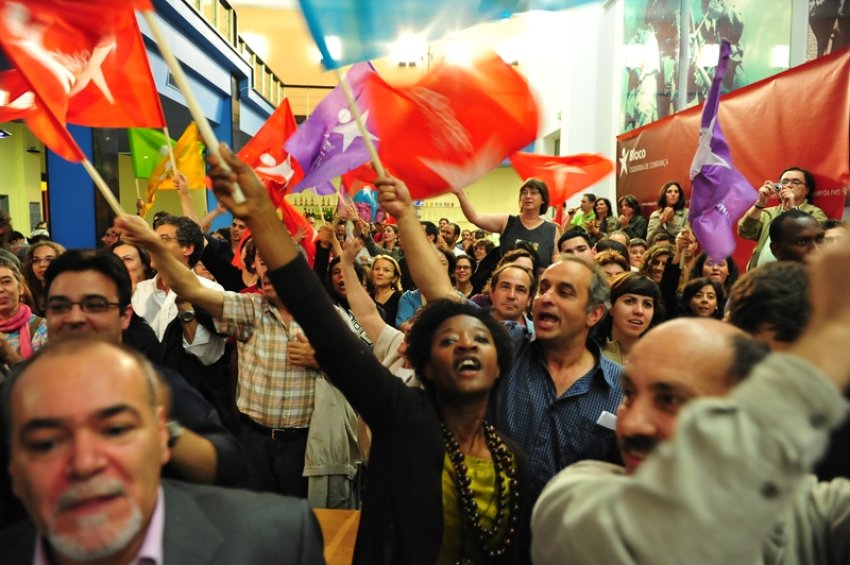 Activists wave left Bloc flags.