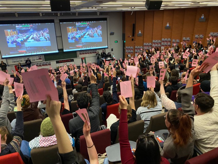 students raise their hands to vote for the motion