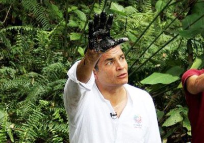 Ecuador's President Rafael Correa raises his oil-stained hand.