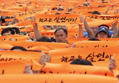 Striking workers from Ssangyong Motor Co., hold up banners reading. “Layoff is murder.”